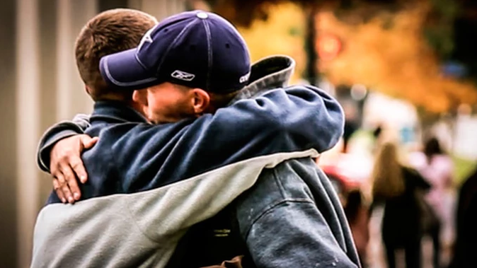 two men wearing coats hugging each other