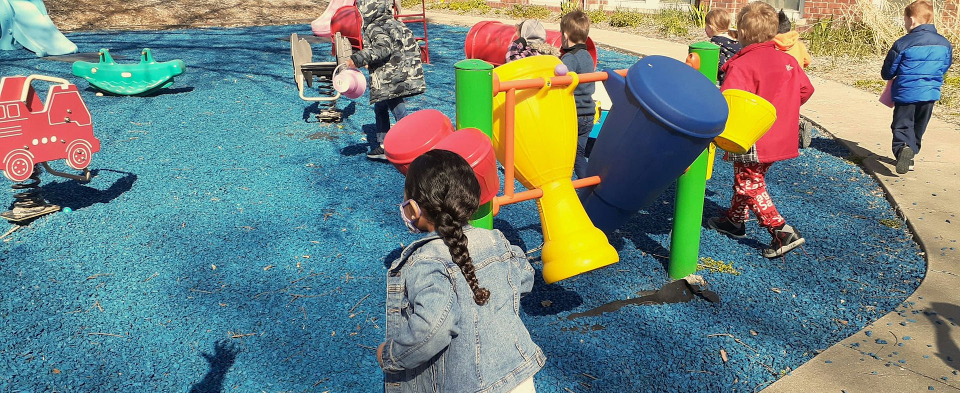 group of young children dressed for cold weather running around on a playground