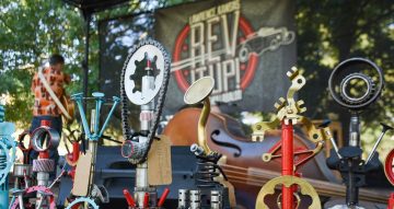 stylized car parts painted and lined up in front of a Rev It Up Hot Rod banner